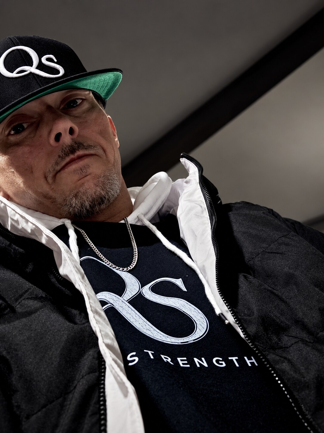 Jonathan wearing the Quiet Strength QS shirt, chain and hat